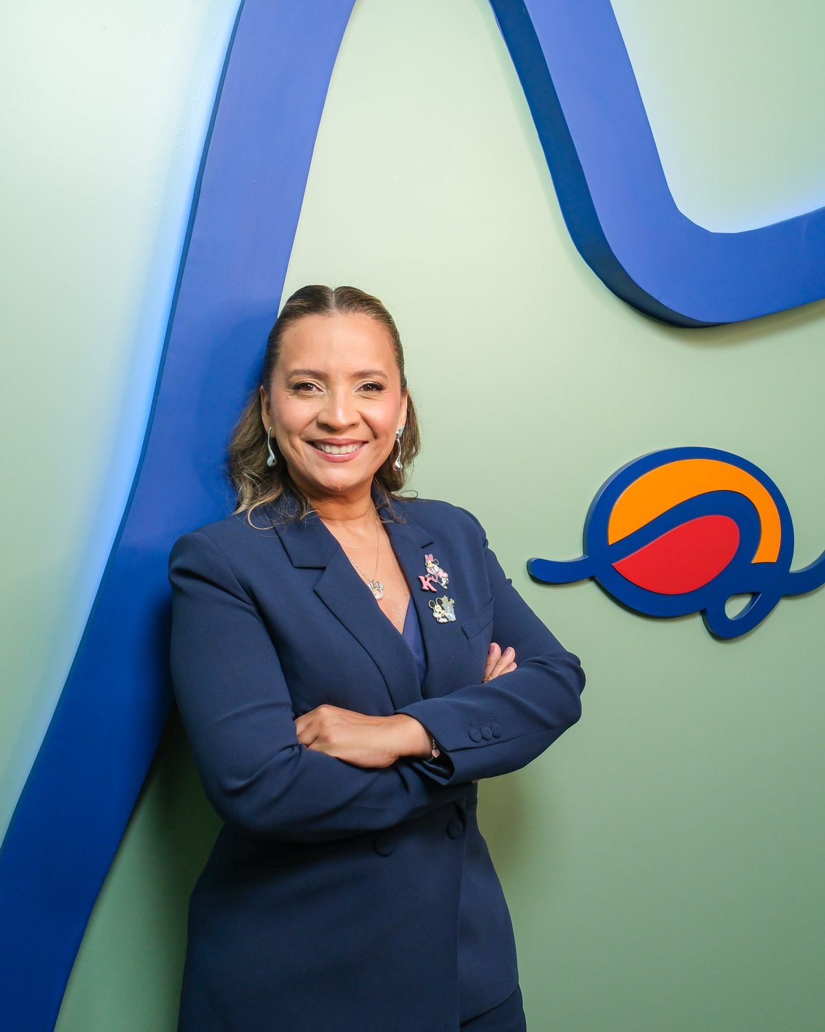 Kennya Martins, psicóloga em Teresina, de braços cruzados diante da parede verde do Instituto Mundo de Dentro